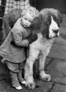 Enfant serrant tendrement son gros chien. Vers 1935. Photographie. Collection particulière.