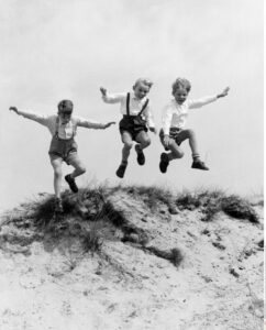 Société. Enfance. Trois garçons sautant dans les dunes. Vers 1955. Photographie. Collection particulière.